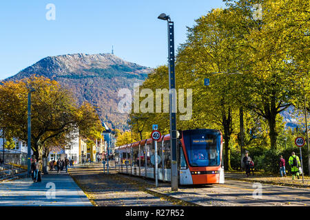 Luce treno Bybanen in Kaigaten, Byparken, nel centro di Bergen, Norvegia. Colori dell'autunno. Mount Ulriken in background Foto Stock