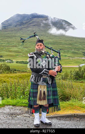 Scozia-luglio 16th: Scotsman giocando bagpipes su strada nelle Highlands su luglio 16,2011 Foto Stock