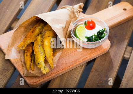 Tapas tradizionali spagnole - deep alici fritte servite con salsa di formaggio cremosa, calce e verdi Foto Stock