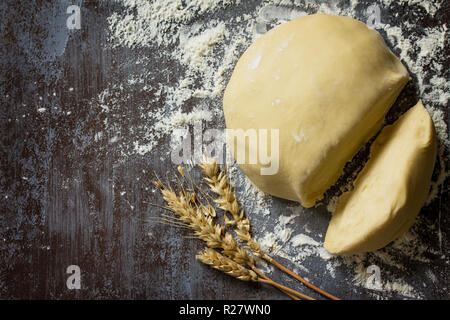 Impasto. Crudo fresco palla di impasto per il pane o la pizza al buio su un tavolo, la cottura dello sfondo. Vista superiore piatta sullo sfondo dei laici. Copia dello spazio. Foto Stock