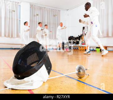 Primo piano della moda moderno ed elegante bella scherma e maschera di rapier sul pavimento in palestra Foto Stock