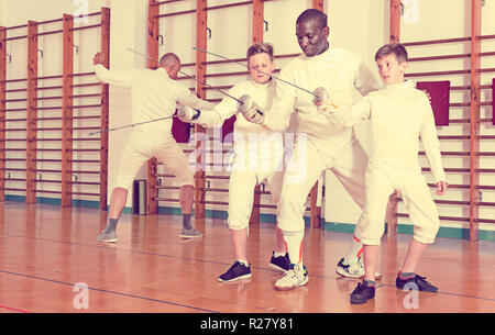 Focalizzato diligente grave ragazzi schermitori attento ascolto professional Efficient friendly scherma pulmann in palestra Foto Stock