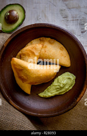 Venezuela e Colombia cibo. Venezuelano di mais tipici empanadas con carne nella terrina di argilla con salsa di avocado. Foto Stock