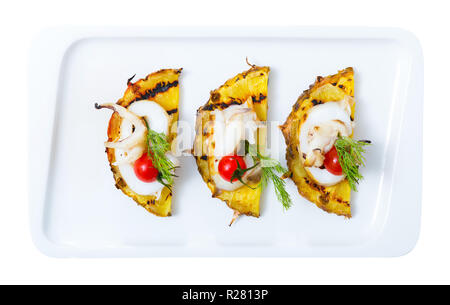 Immagine di seppia fritte su un grill con ananas, pomodorini e salsa Cile sulla piastra. Isolato su sfondo bianco Foto Stock