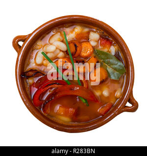 Vista superiore della bulgara tradizionale zuppa di fagioli (bob chorba) con pepe, pomodori, carote e spezie, servito nella pentola di creta. Isolato su sfondo bianco Foto Stock