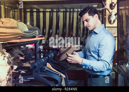 Bel maschio adulto scegliendo apparecchiature di suoneria in negozio Foto Stock