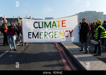 Gli attivisti si vede che trasportano un banner che recita: emergenza climatica. La Ribellione di estinzione attivisti riuniti a cinque ponti principale a Londra, a sollevare le loro preoccupazioni circa il cambiamento climatico e la richiesta che il governo britannico si impegna a ridurre a zero le emissioni di carbonio entro il 2025. Foto Stock