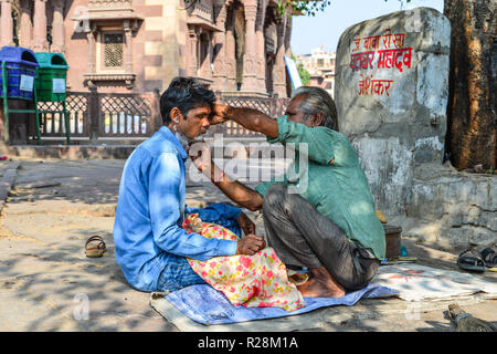 Jodhpur, India - Novembre 6, 2017. Un uomo riceve una barba a una strada barbiere di Jodhpur, India. Jodhpur è la seconda più grande città nello stato del Rajasthan. Foto Stock