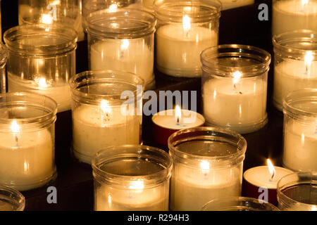 Accendere le candele di fronte ad una statua della Vergine Maria in una chiesa. Foto Stock