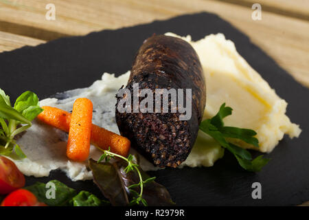 Spagnolo tradizionale salsiccia di sangue con riso servito con purea di patate, carote, pomodoro ciliegino e verdi Foto Stock