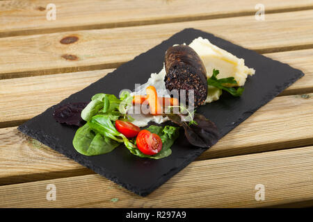 Black Pudding con riso servito con purè di patate, ortaggi e verdure su ardesia Foto Stock