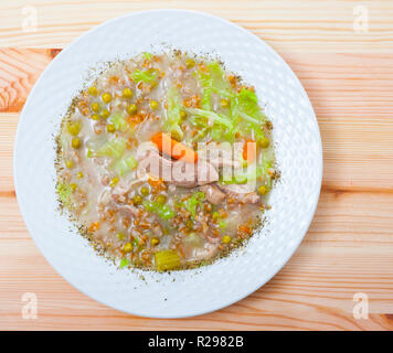 Vista superiore della tradizionale scozzese con brodo di cottura di stinco d'agnello, di orzo, di verdure e piselli serviti in bianco Soup Bowl su sfondo di legno Foto Stock