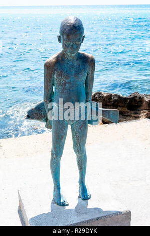 Il piccolo Pescatore" scultura in bronzo di un ragazzo giovane con pesce, porto di Pafo e Paphos (Paphos), Pafos District, la Repubblica di Cipro Foto Stock