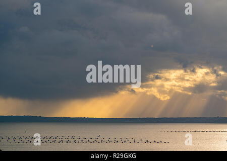 I raggi del sole passano attraverso le nuvole di toccare il mare Foto Stock