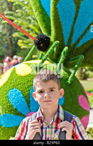 Carino brunette boy undici anni in background di fiori Foto Stock