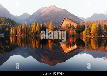 Pittoresca vista autunnale del lago il villaggio di Strbske Pleso negli Alti Tatra National Park, Slovacchia. L'acqua chiara con riflessi arancione di larice e di alta montagna Foto Stock