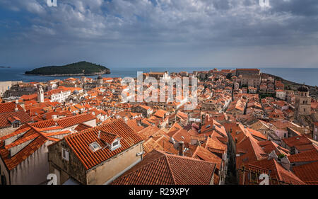 Tetti di vecchie case di Dubrovnik, dal punto di vista della città vecchia cinta fortificata con isola di Lokrum in background Foto Stock