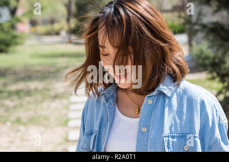 Felice bella donna sorridente sul giorno di estate con il vento che soffia i suoi capelli nel suo viso Foto Stock