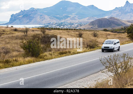 Minivan è in movimento su una strada di campagna in una zona montuosa vicino al lago Foto Stock