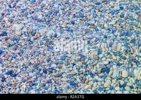 Ciottoli multicolori sotto acqua sulla spiaggia sfondo Foto Stock