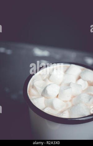 Tazza di cioccolata calda con marshmallows su rustico sfondo di legno. Profondità di campo poco profonda. Immagine a toni. Foto Stock