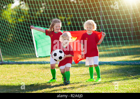 I bambini giocano a calcio sul campo all'aperto. In Portogallo i fan del  team con la bandiera nazionale. Bambini segnare un gol a partita di calcio.  Bambino in portoghese jersey e gancio