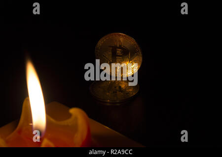 La candela rossa si illumina l'oro crypto curency monete bitcoin e sfondo nero. In aggiunta alla giacente monete, vi sono monete permanente. Foto Stock