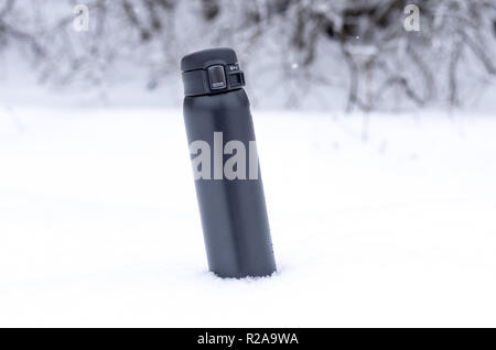 Thermocup nella neve. Test thermos. Thermos nero nella neve. Foto Stock