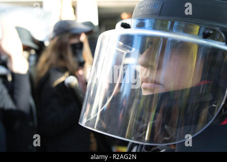 Una sommossa cop guarda mentre i manifestanti sono urlare. Foto Stock