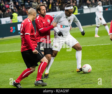 17 novembre 2018, Assia, Frankfurt/Main: Ronaldinho (r), il brasiliano ex calciatore professionista, tenta di prevalere contro Du-Ri Cha (l) e Uwe Bindewald (M). Il calcio brasiliano superstar gareggiato con un team internazionale di ex-football pro contro una selezione di Eintracht Allstars in la Commerzbank Arena. L'ex-pro ha giocato per una buona causa. (A dpa 'Distraction Calcio: Ronaldinho piaga grandi preoccupazioni dopo la carriera' del 18.11.2018) Foto: Andreas Arnold/dpa Foto Stock