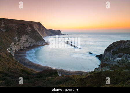 Lulworth, Dorset, Regno Unito. Il 18 novembre 2018. Il sole sorge sull uomo O'guerra bay su Jurassic Coast di Dorset nei pressi di Lulworth su una chiara fredda mattina. Credito Foto: Graham Hunt/Alamy Live News. Foto Stock