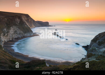 Lulworth, Dorset, Regno Unito. Il 18 novembre 2018. Il sole sorge sull uomo O'guerra bay su Jurassic Coast di Dorset nei pressi di Lulworth su una chiara fredda mattina. Credito Foto: Graham Hunt/Alamy Live News. Foto Stock