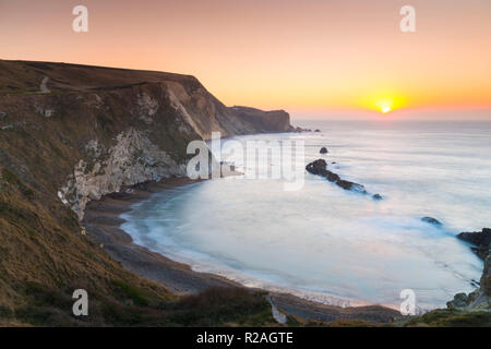Lulworth, Dorset, Regno Unito. Il 18 novembre 2018. Il sole sorge sull uomo O'guerra bay su Jurassic Coast di Dorset nei pressi di Lulworth su una chiara fredda mattina. Credito Foto: Graham Hunt/Alamy Live News. Foto Stock