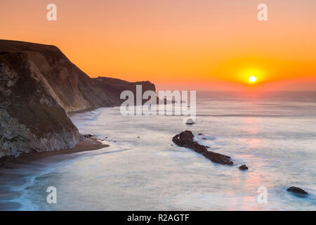 Lulworth, Dorset, Regno Unito. Il 18 novembre 2018. Il sole sorge sull uomo O'guerra bay su Jurassic Coast di Dorset nei pressi di Lulworth su una chiara fredda mattina. Credito Foto: Graham Hunt/Alamy Live News. Foto Stock