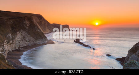 Lulworth, Dorset, Regno Unito. Il 18 novembre 2018. Il sole sorge sull uomo O'guerra bay su Jurassic Coast di Dorset nei pressi di Lulworth su una chiara fredda mattina. Credito Foto: Graham Hunt/Alamy Live News. Foto Stock