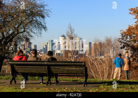Il parco di Greenwich, Londra, Regno Unito, 18 Nov 2018. La gente di stand e guardare il tramonto dal generale Wolfe statua, con viste panoramiche dalla cima della collina verso Canary Wharf. Foto Stock