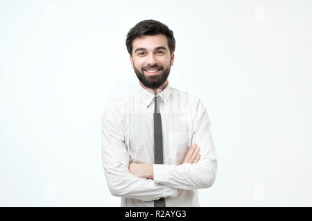 Uomo sorridente con bracci incrociati su sfondo grigio Foto Stock