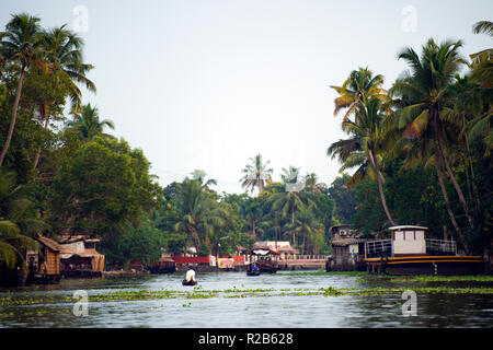 Una canoa e alcune barche a vela sui lussureggianti e verdi backwaters di Alleppey, Kerala, India. Foto Stock