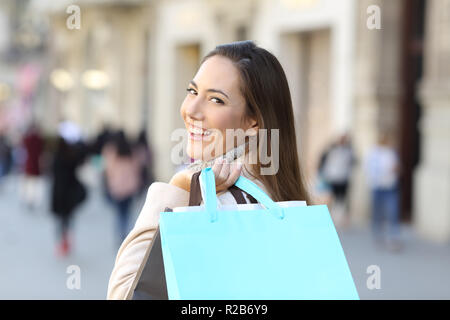 Happy shopper mostra blank shopping bag a piedi in strada in inverno Foto Stock