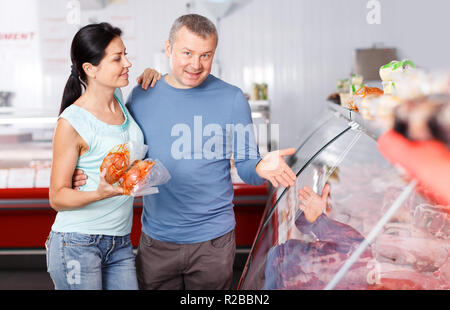 Coppia positiva ai clienti la scelta di carne in macelleria Foto Stock