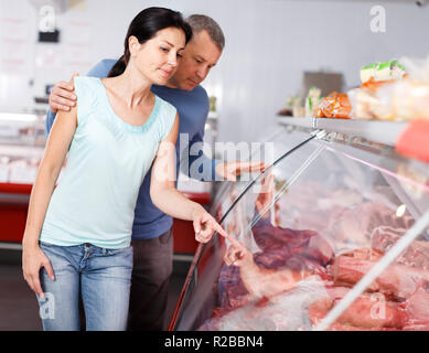 Coppia positiva ai clienti la scelta di carne e di discutere in macelleria Foto Stock