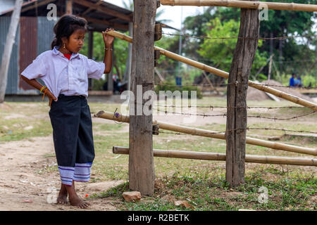 Don Khone, Laos - Aprile 24, 2018: Ragazza accanto a un recinto di mobilia di legno con filo spinato di fronte ad una scuola locale nel sud Laos Foto Stock