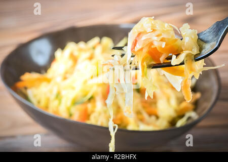 Antipasto di insalata di verdure fermentati crauti le carote e i peperoni in un recipiente e sulla forcella. Concetto di dieta di tendenza cibo vegetariano ricette per fatti in casa Foto Stock