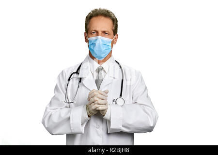 Ritratto di medico con mani giunte. Maschio professionale medico indossa mantello bianco e maschera medico stringe la mano su sfondo bianco. Foto Stock