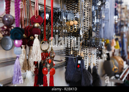 Sacco di orecchini e accessori diversi sul supporto in negozio Foto Stock