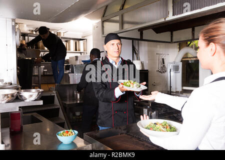 Il personale del ristorante con chef lavorano insieme in cucina Foto Stock