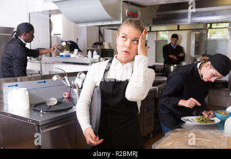 Infelice e stanco giovane cameriera in attesa ordinato piatti nel ristorante cucina Foto Stock