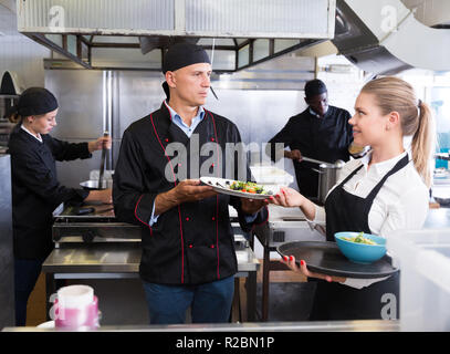 Il personale del ristorante con chef lavorano insieme in cucina Foto Stock