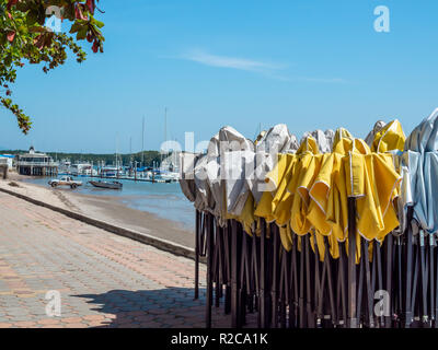 Il vecchio bianco e giallo outdoor tenda pieghevole in piedi sul sentiero esagono blocco in calcestruzzo con sporco sullo sfondo di spiaggia con noleggio barca porta sulla giornata di sole wi Foto Stock