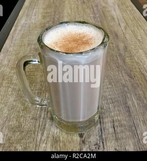 In vetro trasparente riempita di Chai Latte con cannella spruzzata Foto Stock